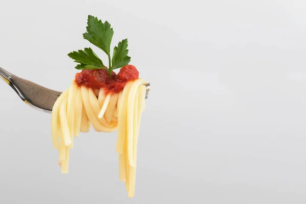 浅灰色背景上带番茄酱和欧芹叶特写的叉子上的意大利面 — 图库照片