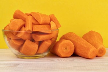 Sarı bir arka plan üzerinde cam bir kapta taze doğranmış havuç