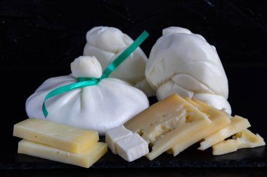 Koyu bir arka plan üzerinde siyah taş tabakta farklı peynir türleri