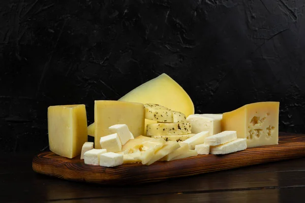 어두운 배경에 도마에 치즈의 — 스톡 사진