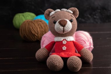 Esmer arka planda komik örülmüş oyuncak ayı. Amigurumi oyuncağı. Tığ işi doldurulmuş hayvanlar..