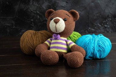 Esmer arka planda komik örülmüş oyuncak ayı. Amigurumi oyuncağı. Tığ işi doldurulmuş hayvanlar..