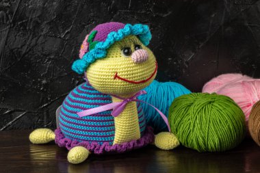 Esmer arka planda komik örülmüş oyuncak kaplumbağa. Amigurumi oyuncağı. Tığ işi doldurulmuş hayvanlar..