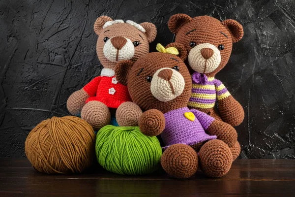 Three Funny Knitted toy bears on a dark background. Amigurumi toy. Crochet stuffed animals.