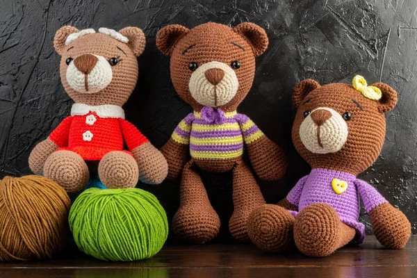 Three Funny Knitted toy bears on a dark background. Amigurumi toy. Crochet stuffed animals.