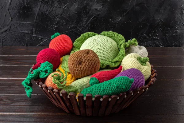 Various toy crochet vegetables on a dark wooden table. Amigurumi toy. Crochet stuffed animals.