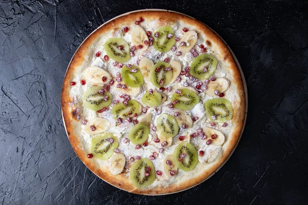 Koyu arkaplanda kivi, muz ve nar meyveli meyveli pizza.