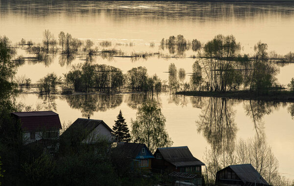 The river spilled from its banks. In water - beach, benches, cabanas, a road. It happens every spring, when ice and snow melt. The river came out of its banks. Spring flood of the river.