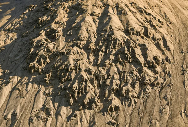 Afbrokkelend zand vanaf de helling van een zanderige heuvel. — Stockfoto