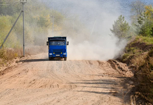 A dump truck with a load goes up the mountain along a dirt road.