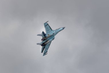 Su 35 avcı uçağı gri bulutların arka planında.