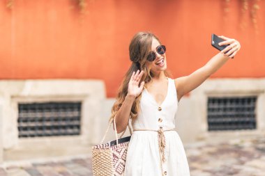 Sokakta odaklanmamış bir arka plan ile bir akıllı telefon kullanan mutlu kadın