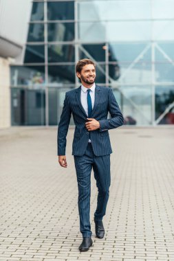 Kameradan uzağa bakarken takım elbisesinin düğmelerini çözen genç bir iş adamının tam uzunlukta fotoğrafı