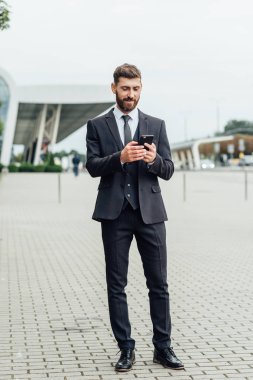 Akıllı telefon kullanan takım elbiseli yakışıklı bir adam.