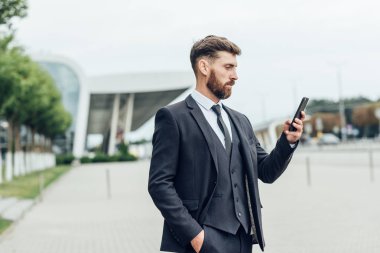 Akıllı telefon kullanan takım elbiseli yakışıklı bir adam.