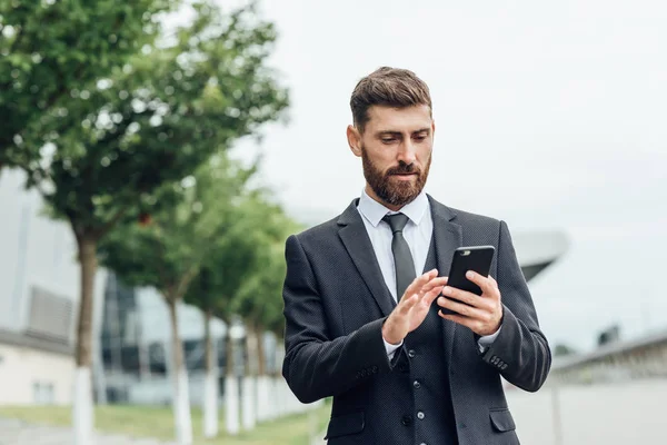 Akıllı telefon kullanan takım elbiseli yakışıklı bir adam.