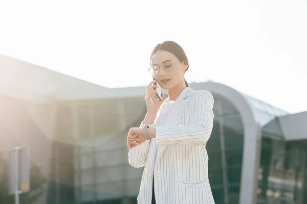Business Woman With Phone Near Office. Portrait Of Beautiful Smiling Female In Fashion Office Clothes Talking On Phone While Standing Outdoors. Phone Communication.