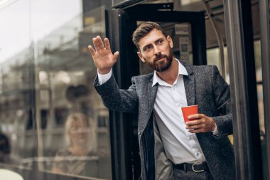 Elinde bir fincan kahve olan takım elbiseli bir adam.