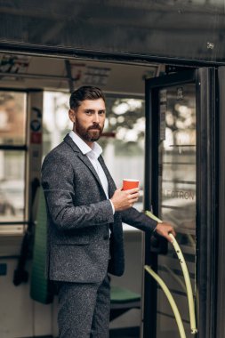 Elinde bir fincan kahve olan takım elbiseli bir adam.