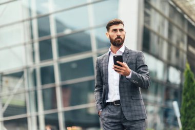 Akıllı telefon kullanan takım elbiseli yakışıklı bir adam.