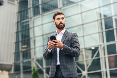 Akıllı telefon kullanan takım elbiseli yakışıklı bir adam.