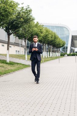 Akıllı telefon kullanan takım elbiseli yakışıklı bir adam.