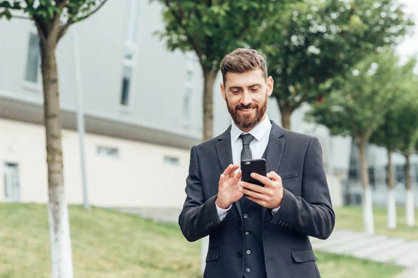 Sokakta cep telefonuyla konuşan genç iş adamı.