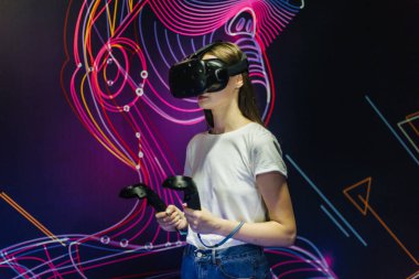 Güzel genç kadın sanal gerçeklik kulaklık ve video oyunları oynarken oyun çubukları.