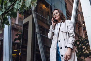 Akıllı telefonla konuşurken cep telefonuyla konuşan bir iş kadını. Mutlu gülümseyen Asyalı / Kafkasyalı iş kadını. 