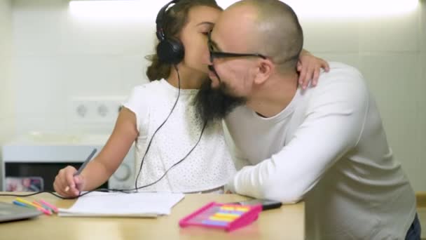 Hija joven le da a papá un beso como él ayuda a las niñas con la tarea después de la escuela. — Vídeos de Stock