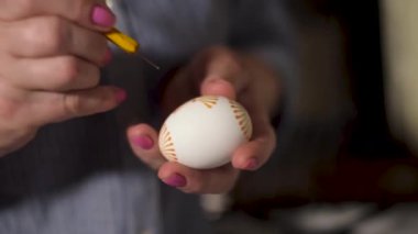 Kadın sanatçı Paskalya yumurtalarını farklı cam kapların arka planında geleneksel bal mumu boyama tekniğiyle süslüyor. Enfes ve sembolik Ukrayna halk tasarım güdülerini kullanarak.