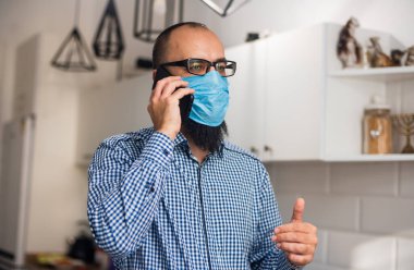 Sakallı ve tıbbi maskeli bir iş adamı. Akıllı telefon kullanan bir iş adamı. Tıbbi maskeli adam cep telefonundan mesaj yolluyor..