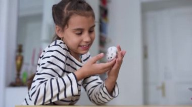 Çocuk, güzel beyaz cüce hamsterla oynuyor. Çocuk kucağında ve küçük bir evcil hayvan besliyor. Evin etrafında çocuklar ve evcil hayvanlar var. Küçük kız sevimli evcil hayvanla ilgileniyor. Sevdiklerinle samimi zaman geçir..