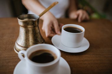 Kadın bir fincan Türk kahvesi masanın üzerine koyar.