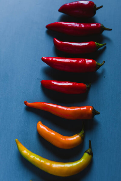 Red, Green And Yelow Chili Peppers Mix On A Blue Background