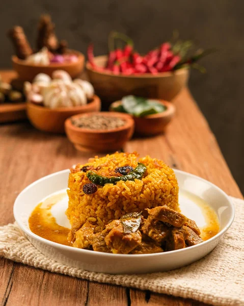 Indian Mutton Biryani Dish served on wooden table. Typical food from India, made from goat meat mixed with spices and basmati rice