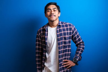 Asyalı öğrenci kameraya gülümsedi ve iki elini de mavi arka plana koyarken kendinden emin görünüyordu. Stüdyo görüntüleri