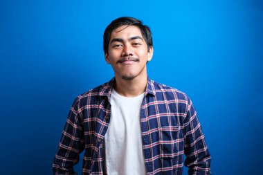 Asyalı öğrenci kameraya gülümsedi ve iki elini de mavi arka plana koyarken kendinden emin görünüyordu. Stüdyo görüntüleri