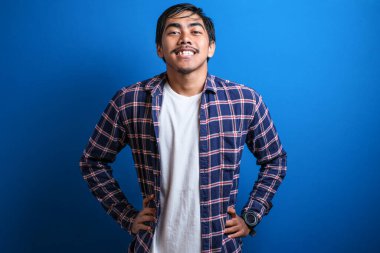 Asyalı öğrenci kameraya gülümsedi ve iki elini de mavi arka plana koyarken kendinden emin görünüyordu. Stüdyo görüntüleri