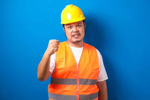 Asian construction worker man wearing orange vest and safety helmet with clenched fist, the man showed an expression of encouragement to his coworker.