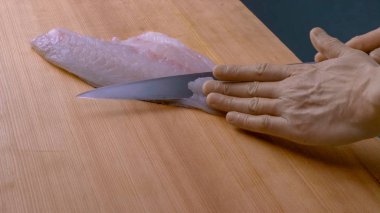 Bir adam tahta bir masada bıçakla balık keser. balık filetosu. Bir adam suşi pişirir. Japon yemekleri