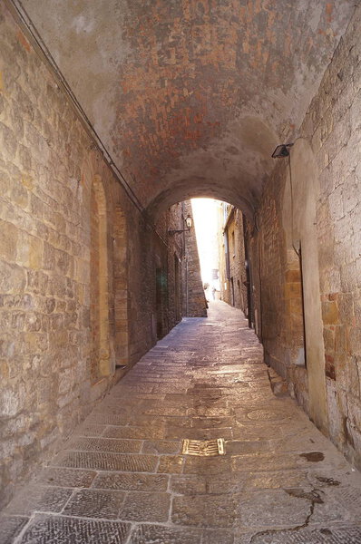 Typical alley with covered passage in Volterra, Tuscany, Italy