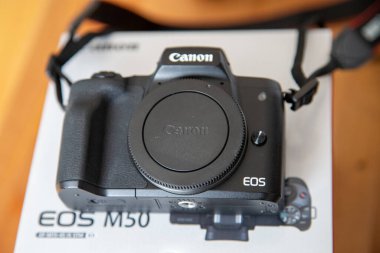Bir Canon EOS M50 aynasız dijital kamera ürünün kutusunun üzerinde lenssiz duruyor..