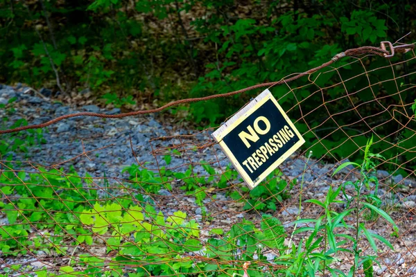 Żółty Czarny Tresspassing Znak Wisi Askew Zardzewiałym Metalowym Drucie Bramy — Zdjęcie stockowe