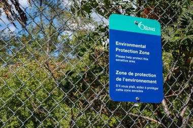 Zincir çitin üzerindeki bir Ottawa Şehri tabelası Carlington Park ziyaretçilerine bölgenin bir Çevre Koruma Bölgesi olduğunu bildiriyor..