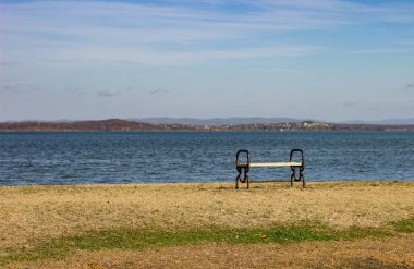 Bir sonbahar gününde deniz kıyısında duran boş yalnız bank.