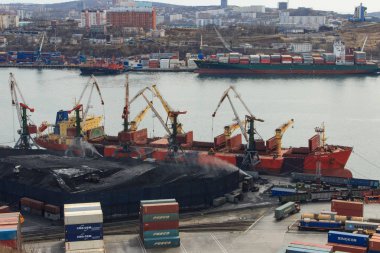 Vladivostok, Rusya - 20 Nisan 2019: Vladivostok limanındaki bir kömür terminalinde açık bir şekilde bir dökme yük gemisine kömür yükleniyor.