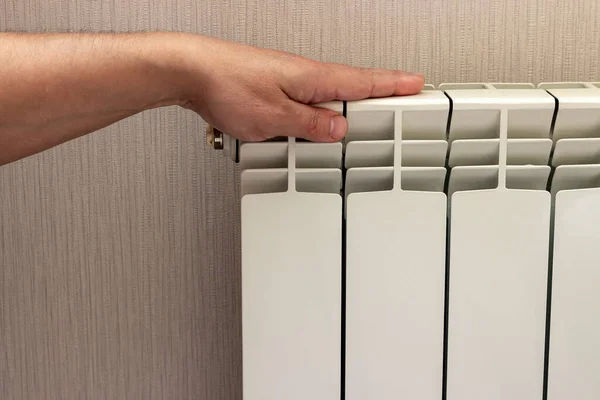 The hand checks the temperature of the radiator, whether it is cold or hot.