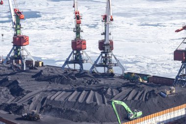 Vladivostok, Rusya - 28 Ocak 2018: Demiryolu vagonlarından Vladivostok limanındaki bir gemiye kömür transferi, çevreye zarar veren açık bir yöntemle gerçekleştirildi.