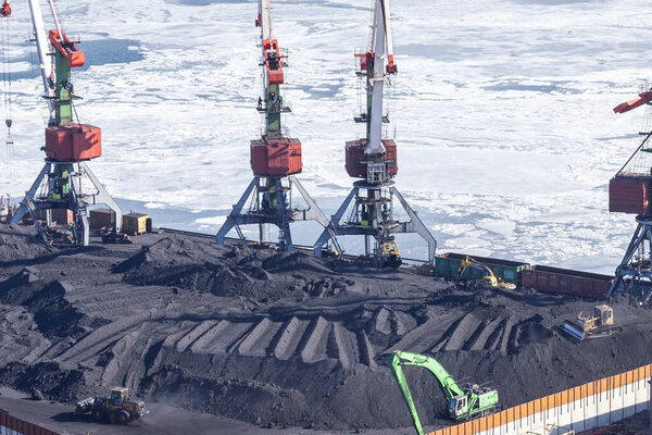 Vladivostok, Russia - January, 28, 2018: Transfer of coal from railway cars to a ship in the port of Vladivostok, carried out by an open method with damage to the environment.